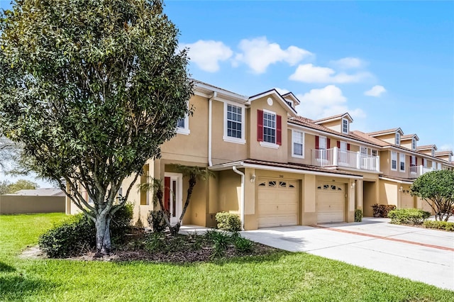 multi unit property with stucco siding, concrete driveway, a balcony, a garage, and a front lawn