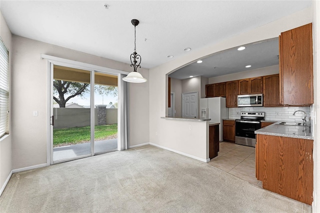 kitchen featuring stainless steel appliances, tasteful backsplash, light carpet, a sink, and baseboards