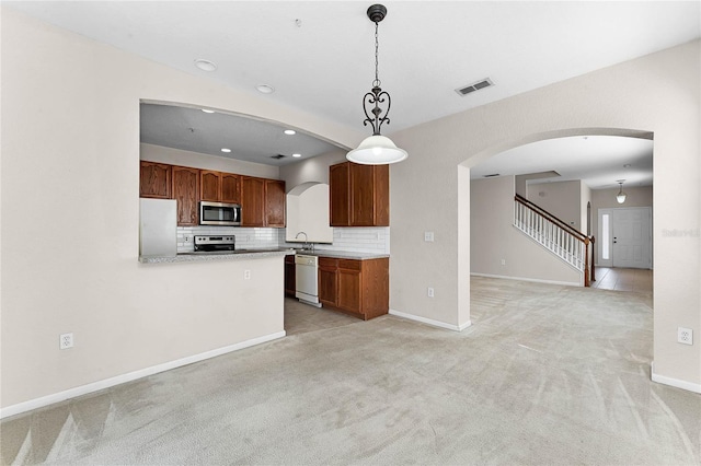 kitchen with light carpet, visible vents, arched walkways, decorative backsplash, and stainless steel appliances