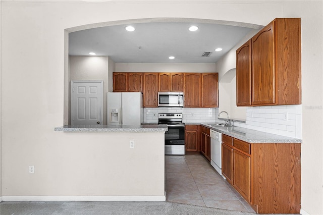 kitchen with visible vents, backsplash, appliances with stainless steel finishes, brown cabinetry, and a sink