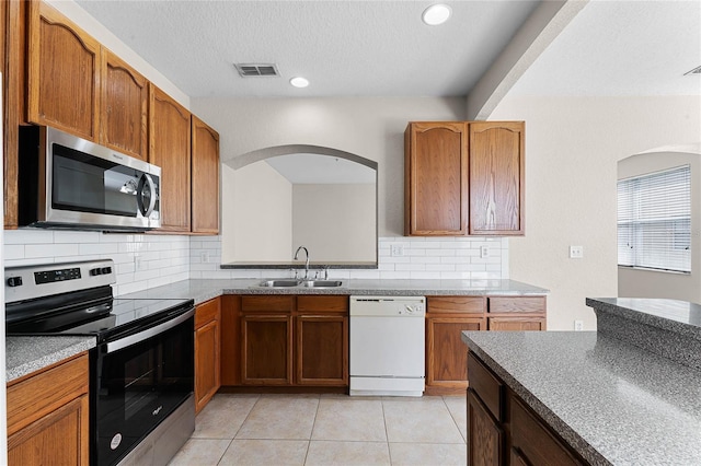 kitchen with visible vents, a sink, stainless steel appliances, backsplash, and light tile patterned flooring