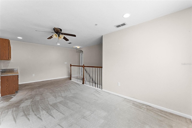 unfurnished room with baseboards, visible vents, arched walkways, and light colored carpet