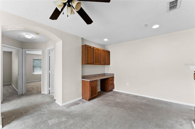 unfurnished office featuring visible vents, arched walkways, baseboards, and built in study area