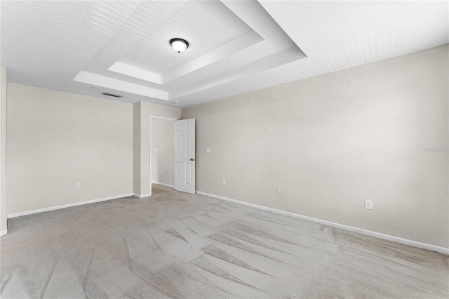 unfurnished room with carpet, a raised ceiling, visible vents, and baseboards