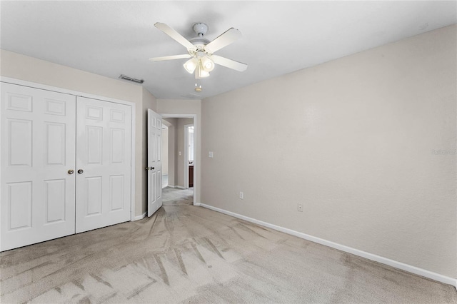 unfurnished bedroom with a closet, visible vents, light carpet, ceiling fan, and baseboards