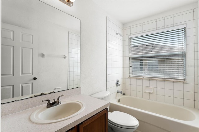 bathroom featuring a textured wall, vanity, toilet, and shower / bathtub combination