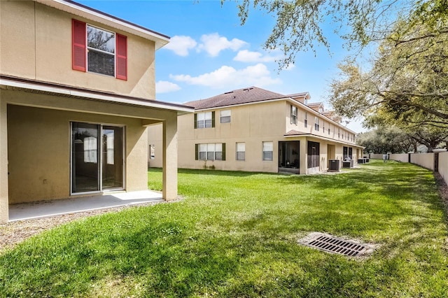 rear view of property featuring central AC, fence, a sunroom, a yard, and stucco siding