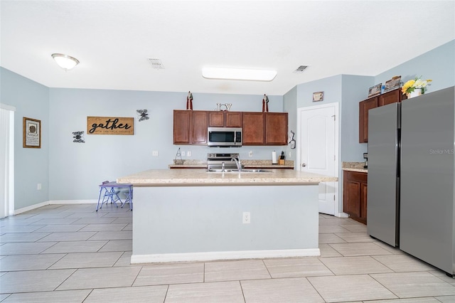 kitchen featuring a sink, visible vents, light countertops, appliances with stainless steel finishes, and an island with sink