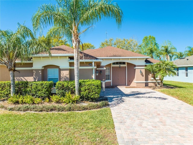 view of front of home with a front yard, decorative driveway, and stucco siding