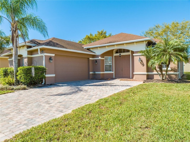 view of front of property featuring a garage, a front lawn, decorative driveway, and stucco siding