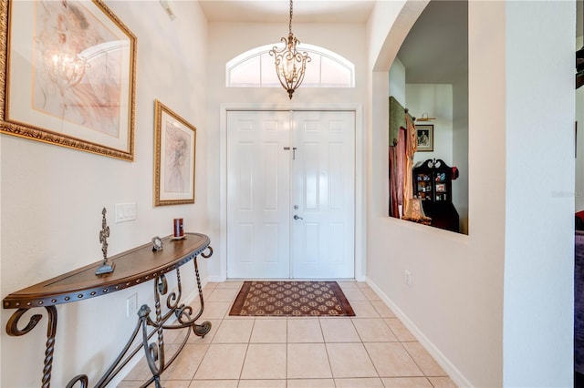 entryway with light tile patterned floors, baseboards, a chandelier, and arched walkways