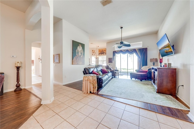 living area with visible vents, arched walkways, baseboards, ceiling fan, and light tile patterned flooring