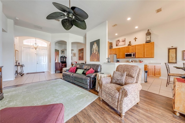 living room with arched walkways, visible vents, light wood-style flooring, and recessed lighting