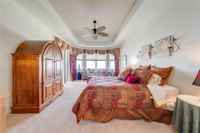 bedroom with light carpet, a tray ceiling, and a ceiling fan