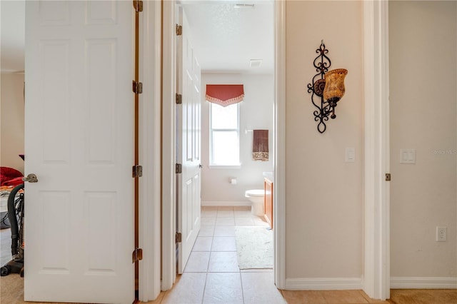 corridor featuring baseboards and light tile patterned flooring