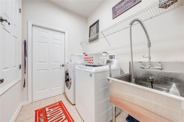 laundry area featuring washing machine and dryer, laundry area, baseboards, and light tile patterned floors