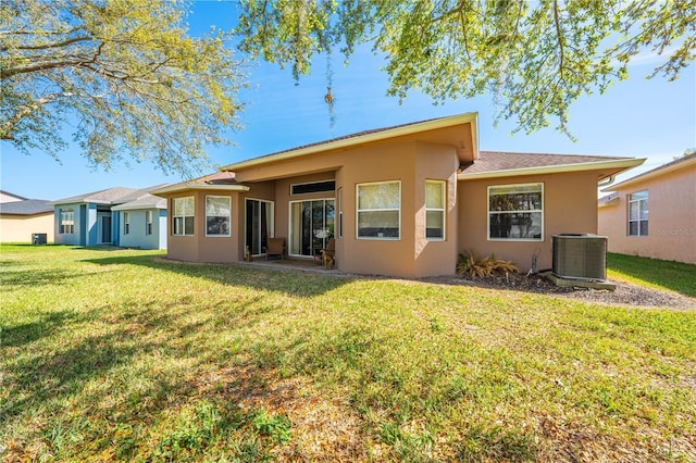 rear view of house with a yard, central AC, and stucco siding