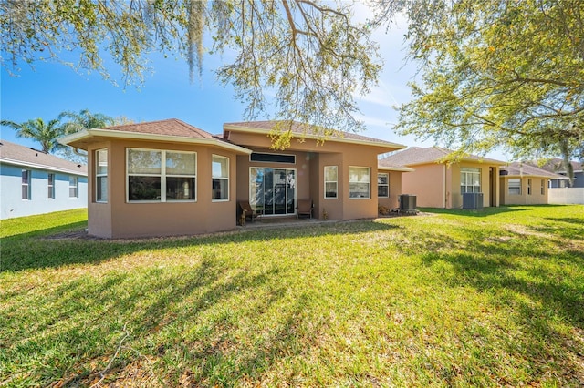 rear view of property with a yard, cooling unit, and stucco siding