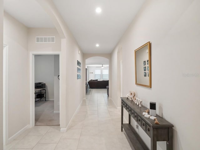 hallway with light tile patterned floors, visible vents, arched walkways, baseboards, and recessed lighting