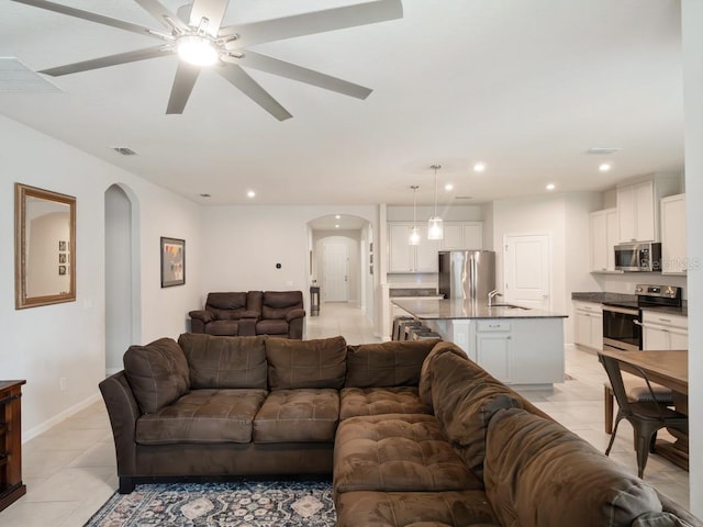 living room with arched walkways, light tile patterned floors, recessed lighting, visible vents, and baseboards