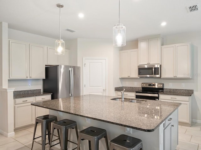 kitchen with dark stone counters, stainless steel appliances, a sink, and visible vents