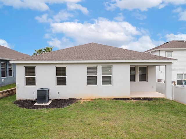 rear view of house featuring roof with shingles, a patio, stucco siding, a lawn, and central AC unit