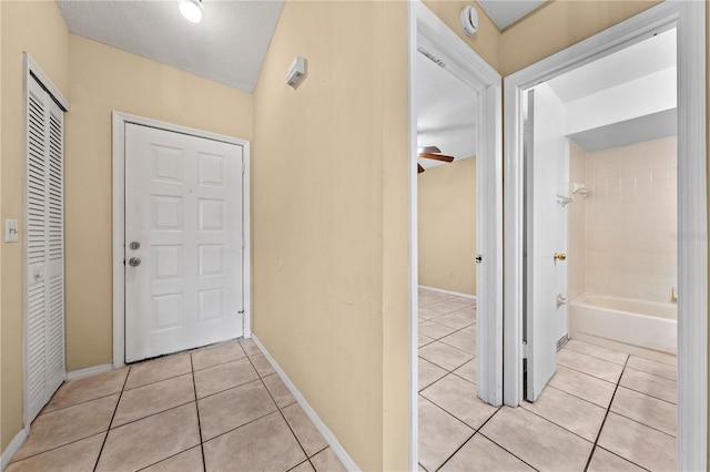 corridor featuring light tile patterned floors and baseboards