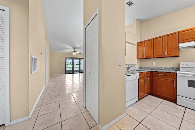 kitchen featuring white appliances, under cabinet range hood, light tile patterned floors, a sink, and a towering ceiling