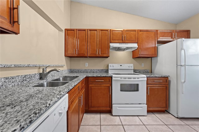 kitchen featuring white appliances, under cabinet range hood, a sink, lofted ceiling, and brown cabinets