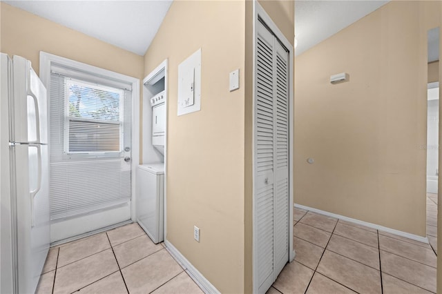 entryway featuring estacked washer and dryer, light tile patterned floors, and baseboards
