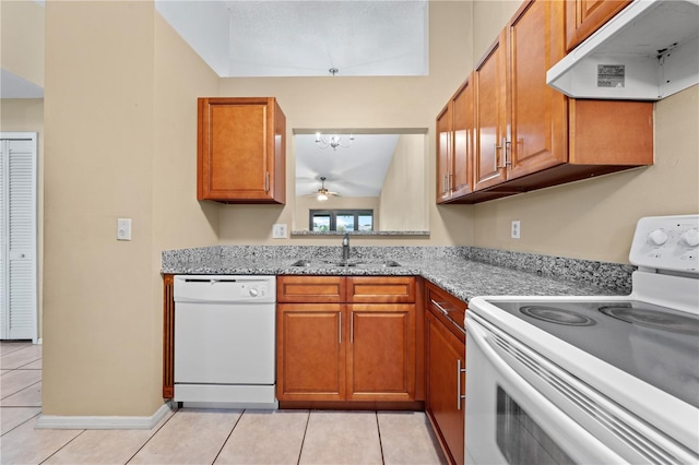kitchen featuring white appliances, under cabinet range hood, a sink, light tile patterned floors, and brown cabinetry