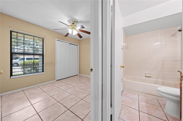 bathroom with a ceiling fan, tile patterned flooring, toilet, baseboards, and shower / bathtub combination