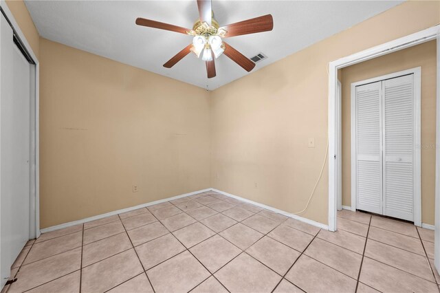 empty room featuring light tile patterned floors, ceiling fan, and baseboards