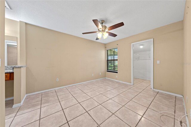 spare room with a ceiling fan, light tile patterned flooring, and baseboards