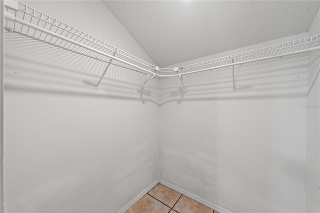 walk in closet with vaulted ceiling and light tile patterned floors