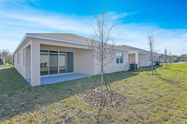 2985 Gavin Sky Dr, Kissimmee, FL 34744 - rear view of property with stucco siding, a shingled roof, central AC, and a yard