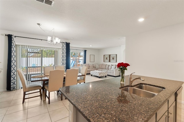 kitchen featuring a chandelier, light tile patterned floors, a sink, visible vents, and an island with sink