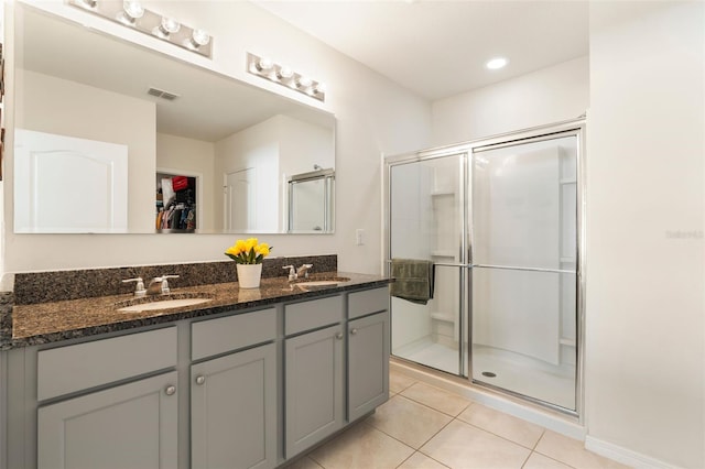 bathroom with a stall shower, visible vents, tile patterned flooring, a walk in closet, and a sink