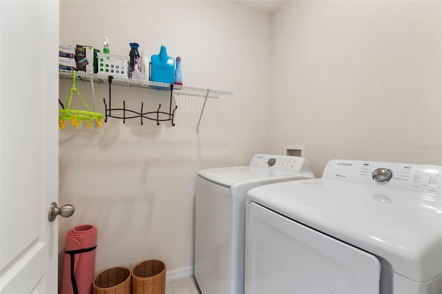 clothes washing area with laundry area, baseboards, and separate washer and dryer