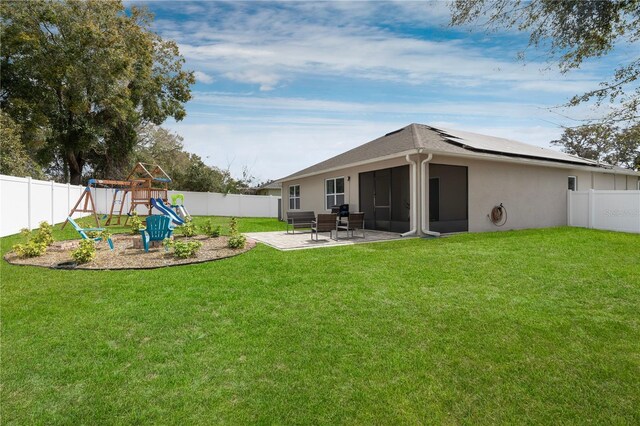 rear view of house featuring a yard, a fenced backyard, a playground, and a patio