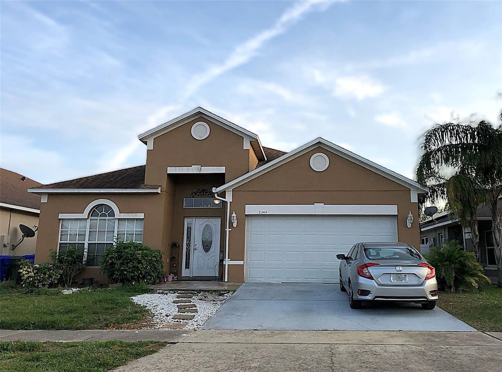 traditional-style home featuring an attached garage, concrete driveway, and stucco siding