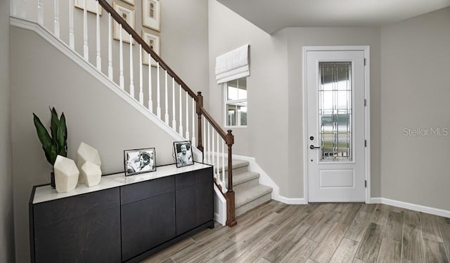 entryway featuring light wood-type flooring, stairway, and baseboards