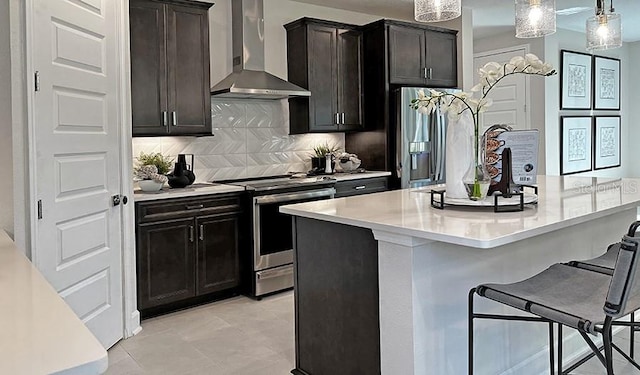 kitchen with decorative backsplash, wall chimney exhaust hood, a breakfast bar, stainless steel appliances, and light countertops