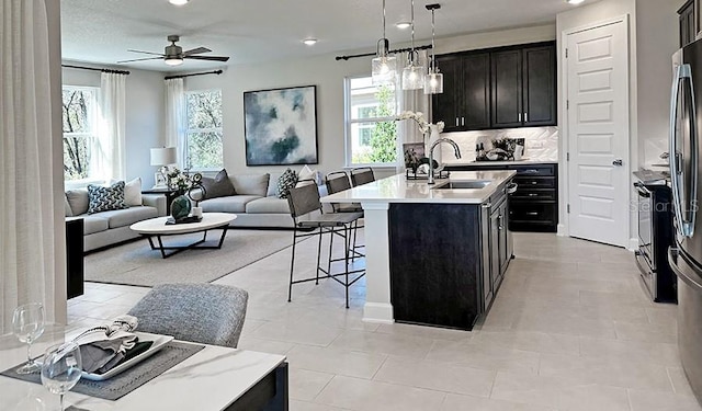 kitchen featuring plenty of natural light, an island with sink, open floor plan, a kitchen breakfast bar, and a sink