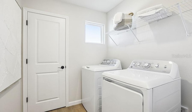 laundry area with light wood-style flooring, laundry area, washer and clothes dryer, and baseboards