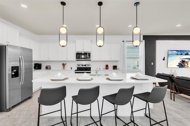 kitchen with appliances with stainless steel finishes, a breakfast bar, light countertops, white cabinetry, and a sink