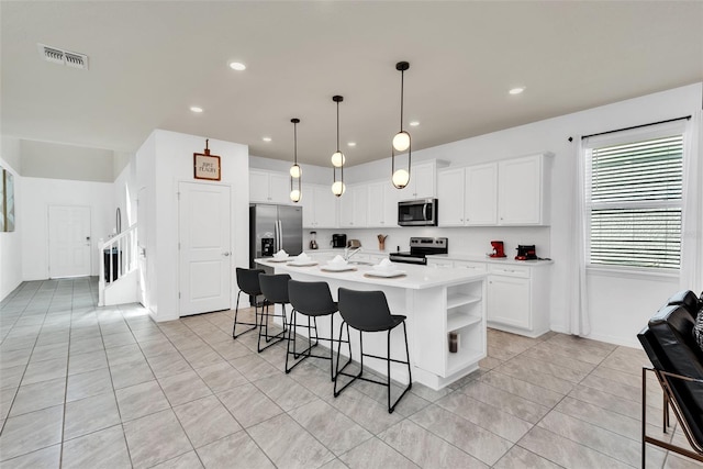 kitchen with stainless steel appliances, light countertops, visible vents, white cabinets, and a kitchen bar