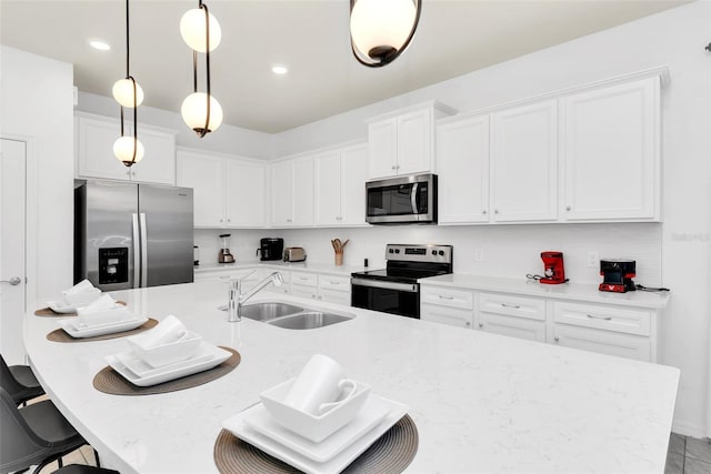 kitchen featuring a breakfast bar area, stainless steel appliances, a sink, white cabinetry, and pendant lighting