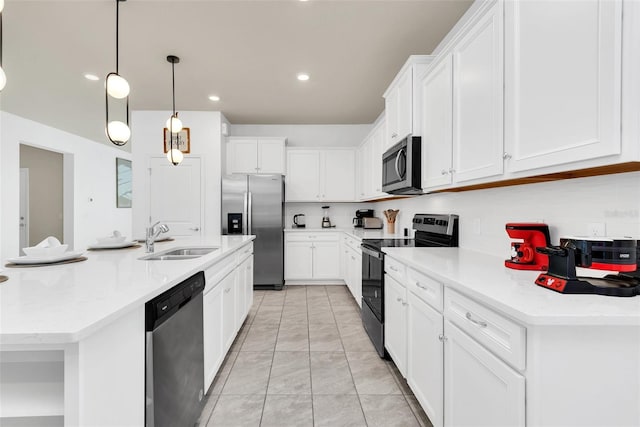 kitchen featuring white cabinets, appliances with stainless steel finishes, hanging light fixtures, a large island with sink, and a sink