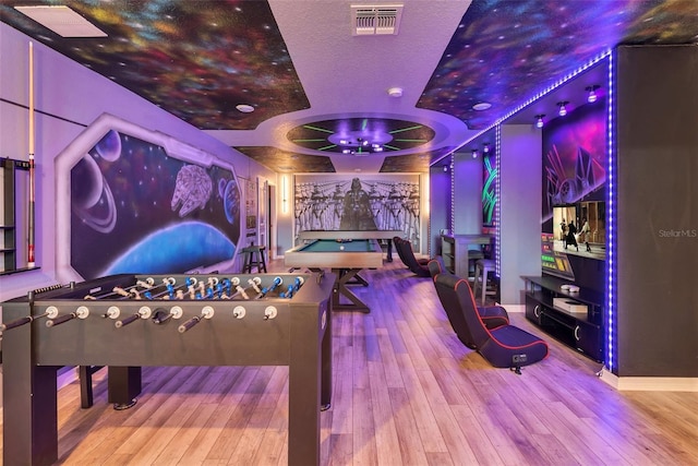 game room with baseboards, visible vents, a raised ceiling, and hardwood / wood-style floors